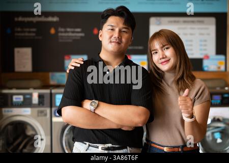 Giovane coppia asiatica fiduciosa nel negozio di lavanderia Foto Stock