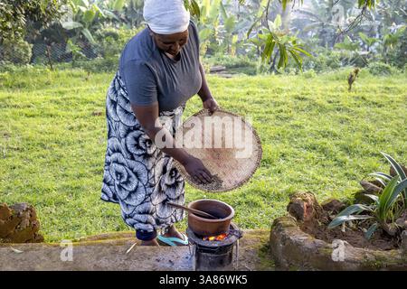 Donna che tosta chicchi di caffè nel villaggio di Ngiresi, Tanzania Foto Stock