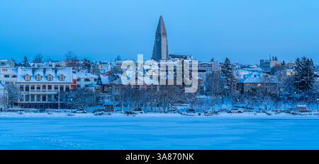 Vista della chiesa di Hallgrimskirkja e dello skyline della città di Reykjavik dal lago Tjornin al tramonto in inverno, Reykjavik, Islanda Foto Stock