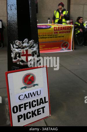 Londra, Regno Unito. 27 marzo 2025. Un cartello dice che "Official Picket" è appoggiato su un bollard della City of London mentre i membri si riuniscono sullo sfondo. Lavoratori, membri della Cleaners and Allied Workers Union (CAIWU) picchetto fuori dalla Central London Criminal Court (Old Bailey) in Newgate Street, Londra. Essi si oppongono alla privatizzazione dei loro posti di lavoro. La City of London Corporation sta progettando di trasferirli a nuovi contratti in outsourcing. I lavoratori temono per il loro futuro e sostengono che ciò comporterà retribuzioni inferiori e carichi di lavoro più pesanti. Credito: SOPA Images Limited/Alamy Live News Foto Stock