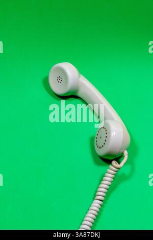 Ricevitore grigio del vecchio telefono su una superficie verde Foto Stock