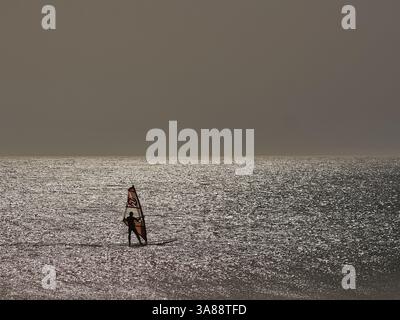 Windsurfer che cavalca le onde a Tarifa, in Spagna, con venti forti, acqua turchese e un'atmosfera avventurosa sulla costa meridionale dell'Andalusia Foto Stock