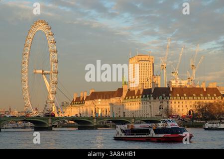 Una barca City Cruises trasporta i passeggeri sul Tamigi oltre il London Eye e la County Hall, offrendo vedute panoramiche della South Bank di Londra al tramonto Foto Stock