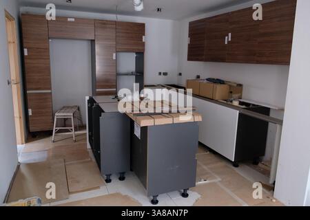 Installazione di moderni armadietti da cucina e isola in corso come parte di una ristrutturazione o di una nuova costruzione. Foto Stock