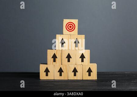 Targeting. Piramide di cubi con frecce che puntano verso uno con un mirino sulla parte superiore su sfondo grigio Foto Stock