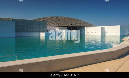 Abu Dhabi, Emirati Arabi Uniti - 10 gennaio 2024, Vista panoramica della facciata bianca neve del Louvre Abu Dhabi con una cupola in metallo circondata dall'acqua, Foto Stock