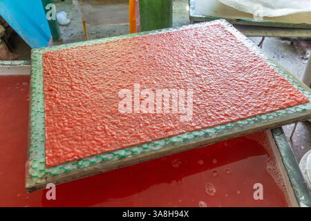 Polpa di carta rosa su una sganciatura pronta per l'asciugatura al Papierus Art and Craft di Kalibo, Filippine, che mostra le tradizionali tecniche di fabbricazione della carta artigianale Foto Stock