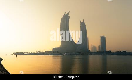 Doha, Qatar [24 febbraio 2025]: Una mattinata nebbiosa a Doha con grattacieli parzialmente nascosti nella nebbia, creando un paesaggio urbano misterioso e sereno. Foto Stock