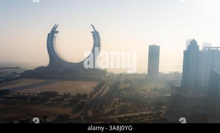Doha, Qatar [24 febbraio 2025]: Una mattinata nebbiosa a Doha con grattacieli parzialmente nascosti nella nebbia, creando un paesaggio urbano misterioso e sereno. Foto Stock