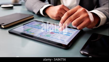 Uomo afroamericano concentrato che analizza i dati finanziari su software informatici. Foto Stock