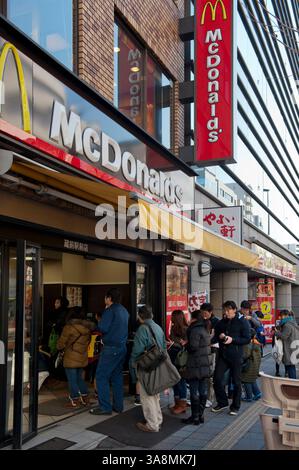 Una lunga fila di clienti che aspettano fuori da un fast-food americano McDonald's nel quartiere Asakusa di Tokyo, Giappone. Foto Stock