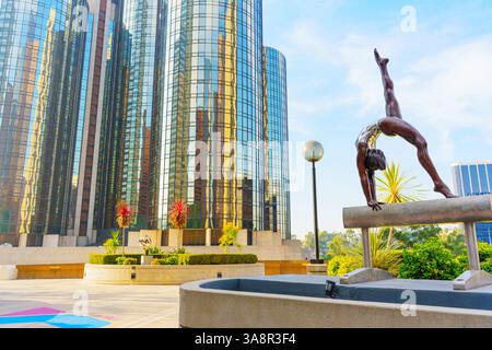 Los Angeles, California - 4 dicembre 2024: Scultura in bronzo di una ginnasta che si esibisce su un cavallo di pommel di fronte ai moderni grattacieli presso la YMCA Cour Foto Stock