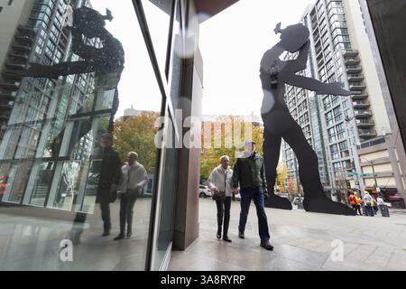 18 ottobre 2017 - Seattle, Washington, Stati Uniti - Seattle, Washington: Una coppia cammina accanto all'uomo martellante al Seattle Art Museum mentre la prima tempesta della stagione colpisce la città con forti venti e pioggia. Il National Weather Service ha un avviso di vento forte in vigore e un avviso di pioggia pesante durante il fine settimana per la maggior parte della Washington occidentale. (Immagine di credito: © Paul Gordon via ZUMA Wire) Foto Stock
