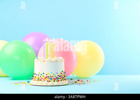 Deliziosa torta bento con spruzzette colorate e candele accese sul tavolo azzurro. Spazio per il testo Foto Stock