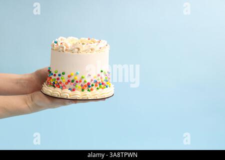 Donna che tiene in mano una deliziosa torta bento con spruzzi colorati su sfondo azzurro, primo piano. Spazio per il testo Foto Stock