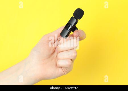 Donna con microfono lavalier su sfondo giallo, primo piano Foto Stock