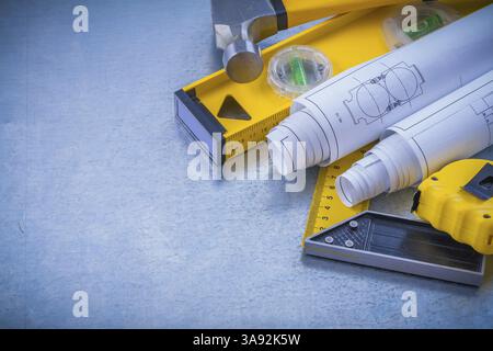 Il nastro di misurazione a martello presenta il concetto di manutenzione del righello quadrato di livello da costruzione su fondo metallico industriale Foto Stock
