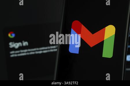 Il logo Gmail viene visualizzato sullo schermo di uno smartphone, con la pagina di accesso gmail visibile sullo schermo di un computer sullo sfondo Foto Stock