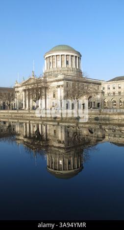 Dublino, Irlanda - 22 gennaio 2015 - il fiume Liffey lungo Inns Quay in una giornata di sole con le quattro Corti e il cielo azzurro che si riflette nell'acqua ferma Foto Stock