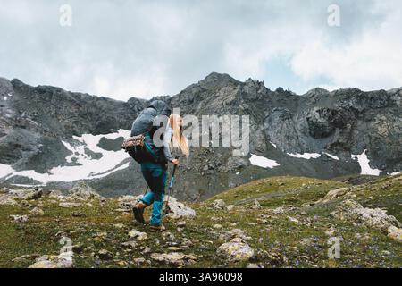 Donna viaggiatrice arrampicata sulle montagne con zaino pesante viaggio avventura estrema stile di vita sano escursioni da sola donna escursionista che esplora la natura selvaggia, Foto Stock