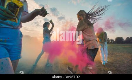 I giovani che celebrano il festival holi, lanciano polvere colorata al tramonto, si divertono insieme Foto Stock