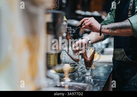 Il barista prepara bevande gourmet con particolare attenzione al processo di estrazione Foto Stock
