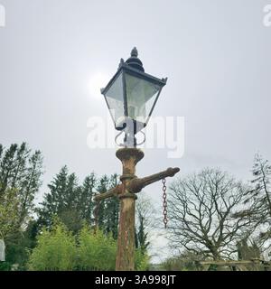 Una foto malinconica di una vecchia lampada a gas vittoriana arrugginita realizzata in ghisa e vetro, scattata a Stydd Gardens, Ribchester, Regno Unito. Foto Stock