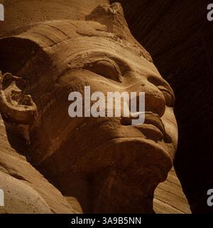 Graffiti che deturpano la guancia di pietra dell'antico faraone egiziano del nuovo Regno, Ramses II, su uno dei quattro colossi del potente sovrano che fiancheggiano l'ingresso al grande Tempio che ha costruito ad Abu Simbel nel deserto nubiano circa 3.300 anni fa. Foto Stock
