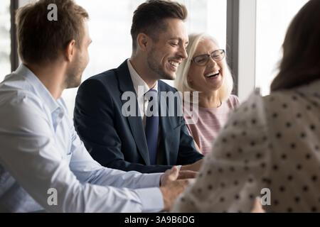 Gruppo di professionisti, sorridenti e risi impegnati in una conversazione Foto Stock