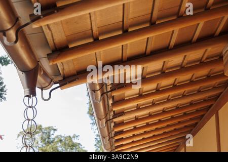 Il tetto in tessuto di legno di bambù di stile giapponese eroga gocce di pioggia e catena di pioggia, design architettonico tradizionale Kusaritoi. Foto Stock