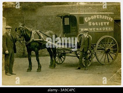 Cartolina originale dell'epoca della prima guerra mondiale di un uomo della classe operaia e del suo apprendista in piedi accanto a un carro per la consegna di generi alimentari, cavallo e carro d'epoca. Carro trainato da cavalli vittoriani. Cartellonistica pubblicitaria Cooperative Society (la cooperativa), Walmer & Deal (area) sul lato. Walmer / Deal in Kent, Inghilterra, Regno Unito circa 1914 Foto Stock