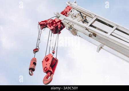 Testa del gancio della gru del paranco da vicino per il sollevamento di carichi pesanti, braccio della macchina per l'edilizia nel cielo. Foto Stock