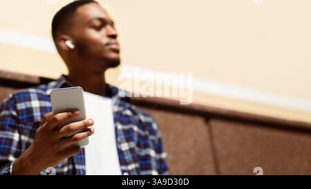 Ritratto dell'uomo che ascolta la musica appoggiata al muro Foto Stock