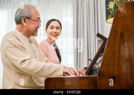 Giovane donna asiatica che insegna pianoforte per l'insegnamento di un uomo anziano Foto Stock