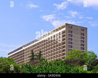 Grande hotel a piu' piani con balconi adagiati contro il cielo blu, circondato da una lussureggiante vegetazione verde Foto Stock
