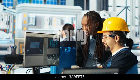 Esperto di impianti per pannelli solari che istruisce il tecnico su come sfruttare al meglio l'energia solare. Una fabbrica di fotovoltaici afroamericana ricercatore mostra ai lavoratori come migliorare l'efficienza, telecamera B. Foto Stock
