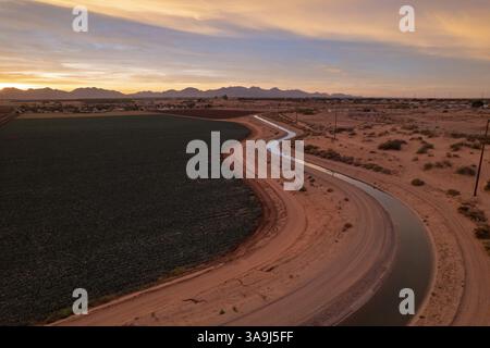 Vista aerea dei terreni agricoli e del canale di irrigazione all'alba vicino a Yuma, Arizona, mostrando l'agricoltura del deserto e la luce del mattino presto. Foto Stock
