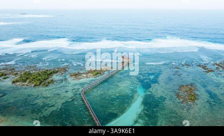 Vista aerea mozzafiato della spiaggia Cloud 9 a Siargao: Una splendida distesa di sabbia bianca, acque turchesi e una passeggiata panoramica in legno sull'Ocea Foto Stock