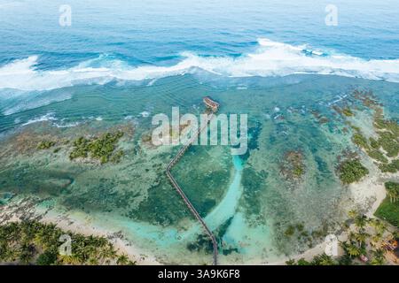 Vista aerea mozzafiato della spiaggia Cloud 9 a Siargao: Una splendida distesa di sabbia bianca, acque turchesi e una passeggiata panoramica in legno sull'Ocea Foto Stock