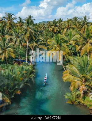 Crociera panoramica sul fiume Maasin a Siargao - Un tranquillo viaggio attraverso le lussureggianti acque costeggiate da palme, con la famosa palma Bent Palm Tree e le splendide acque tropicali Foto Stock