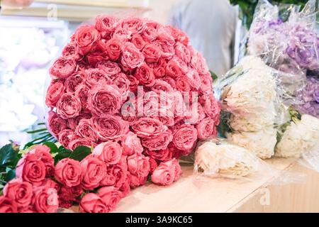 Un bouquet di rose rosa e bianche siede su un tavolo. Le rose rosa sono al centro del bouquet, con le rose bianche che le circondano. L'accordo Foto Stock