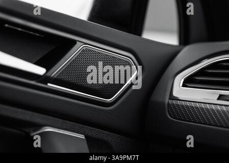 Angolo della portiera anteriore e del pannello anteriore in un'auto. Interni della nuova vettura con altoparlante del sistema audio e rivestimento in fibra di carbonio. Foto Stock