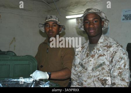 13 marzo 2005; AR Ramadi, Iraq; diciottenne PFC. DARIUS D. GAGE, (a destra) uno specialista di servizi alimentari con quartier generale e compagnia di servizi, 1st Battalion, 5th Marine Regiment, possiede per una foto fuori dalla sala caos qui. OSCAR E. SECAIDA, specialista di ristorazione, mani, 1° Battaglione, 5° Marines, da Houston, sta accanto a lui. Farsi fotografare non è una novità per Gage. I nativi di Chicago hanno modellato l'abbigliamento per quattro anni su Essence Magazine prima di unirsi all'estate dei Marines del 2004. Spesso ha fatto più di 00 per aver fatto 24 ore di modellazione. Si è Unito alla Foto Stock