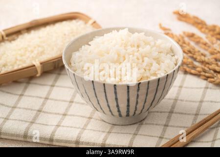 Una ciotola di riso bianco appena cucinato, morbido, soffice e leggermente lucido su sfondo bianco del tavolo. Foto Stock