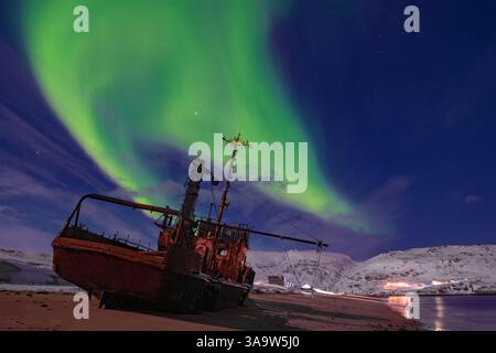 Aurora Boreale sopra un vecchio peschereccio a strascico in una notte di marzo. Teriberka. Regione di Murmansk, Russia Foto Stock