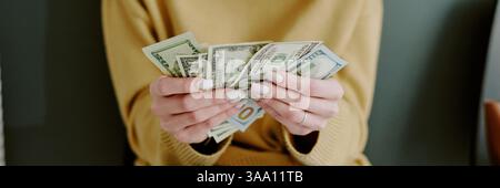 Mani che tengono e contano vari tagli di denaro in primo piano. L'immagine presenta una vista dettagliata di dita e unghie, fornendo un contesto finanziario Foto Stock