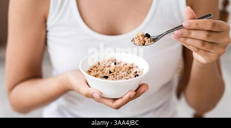Tagliata di donna che tiene la ciotola con granola fatta in casa Foto Stock