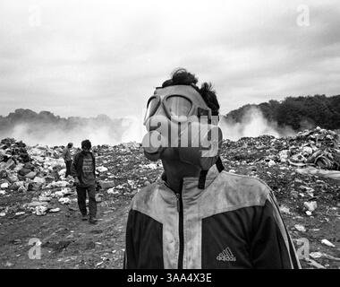 30 gennaio 2007; Ohrid-Resen, MACEDONIA; globalmente, il fumo domestico uccide una persona ogni 20 secondi. Quest'uomo modella una maschera antigas che ha appena trovato nella discarica di Bukovo a Ohrid-Resen. La maggior parte dei raccoglitori di rottami deve lavorare tutto il giorno nel fumo acrido dai rifiuti in fiamme. Il fumo si propaga lungo la valle causando problemi ai conducenti su strada. I rom della classe media più redditizia dal punto di vista economico si sono ben integrati con la più ampia comunità macedone, vivono negli stessi quartieri, mandano i loro figli nelle stesse scuole e gestiscono le loro attività. La maggior parte dei rom, però, Foto Stock