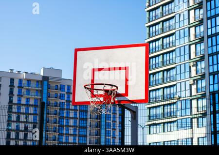 Di fronte a edifici architettonici moderni, si erge un canestro da basket che unisce sport e vita urbana Foto Stock