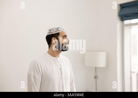 Un uomo arabo pensivo vestito di disdasha che guarda in lontananza Foto Stock
